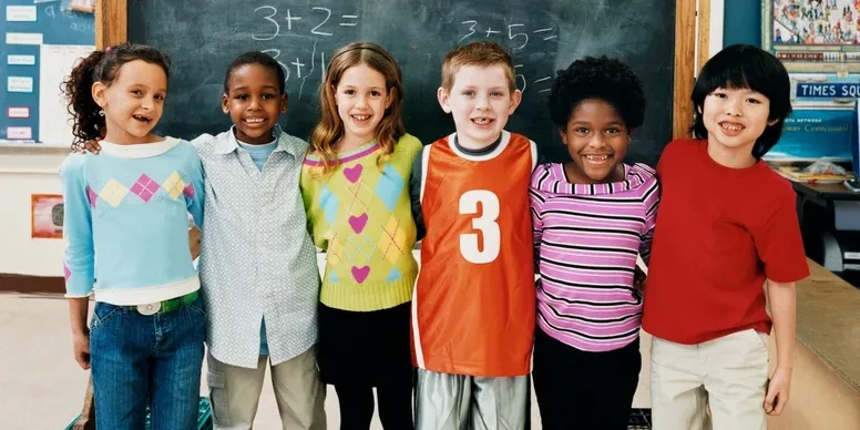Six children smiling together in a classroom